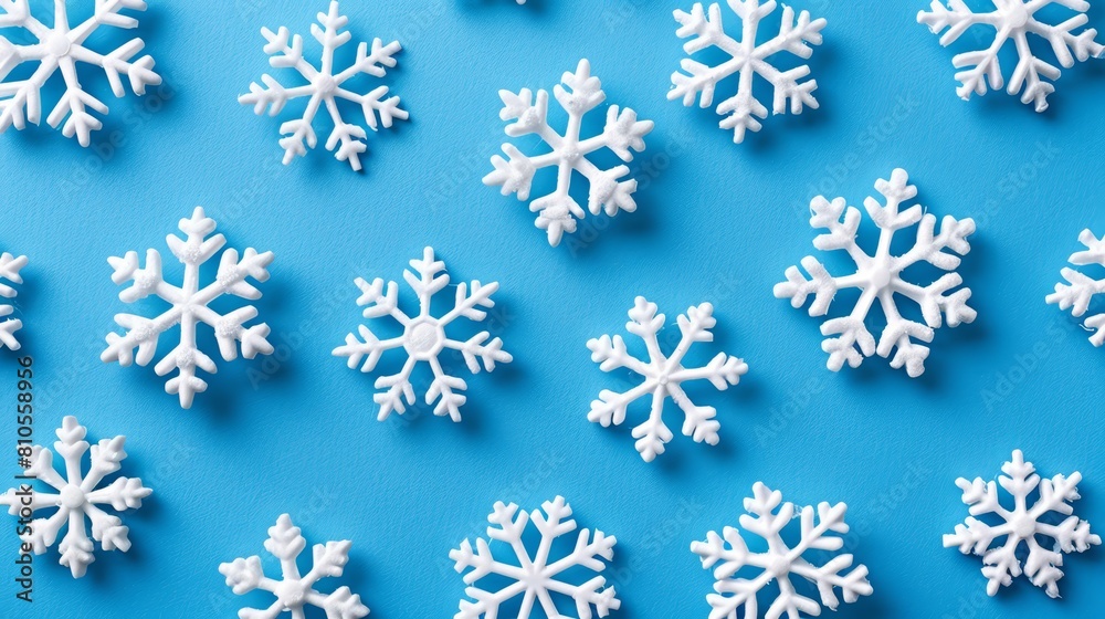   A group of white snowflakes sits atop a blue surface, each one shaped as a distinct snowflake