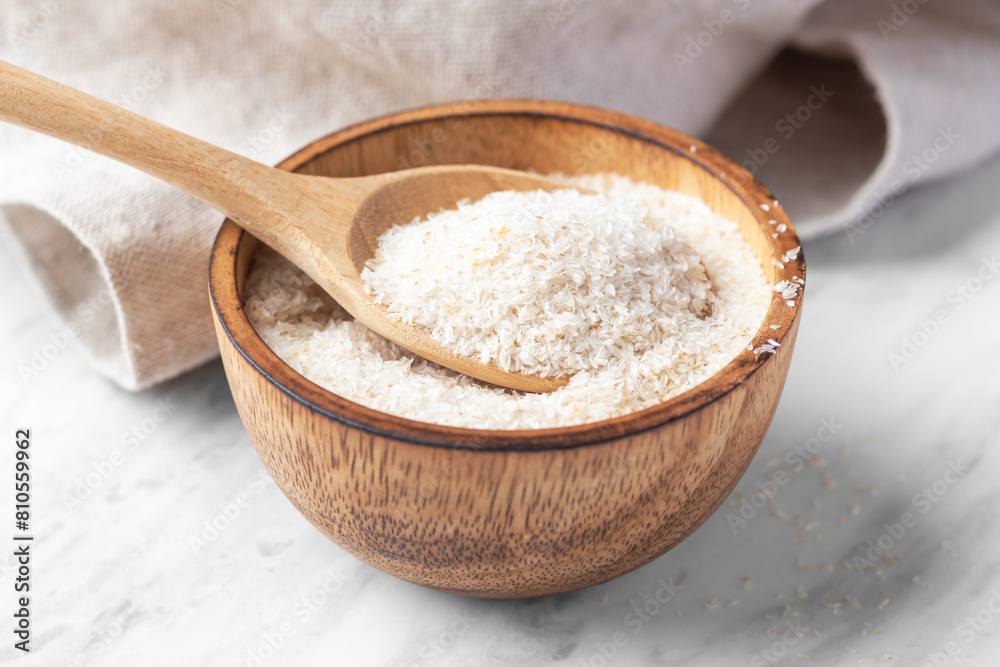 Psyllium husk in spoon and wood bowl, fiber food for diet on white marble table Psyllium husk in spoon and wood bowl, fiber food for diet on white marble table