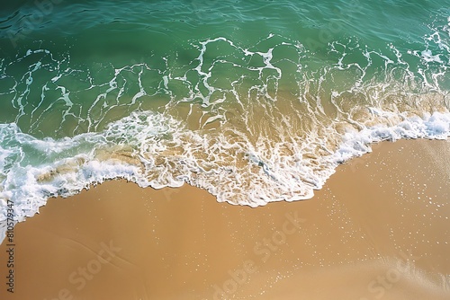 The top view of the beach with the soft wave of the green sea and the yellow sand.