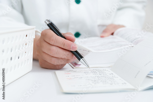 お薬手帳で薬の確認をしている調剤薬局の薬剤師の手元