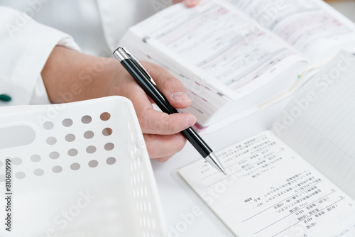 お薬手帳で薬の確認をしている調剤薬局の薬剤師の手元