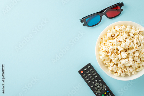 Home theater setup with snacks: Overhead shot of savory popcorn, 3D glasses, and streaming remote. Pastel blue backdrop, perfect for party ads or text insertion