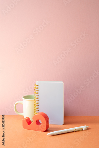 Obraz na płótnie Workspace office desk with notebook, mug cup, pen, tape dispenser. pink orange background w salonie