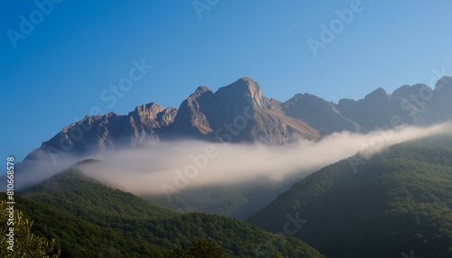 Mountains shrouded in mist under a clear blue sky © Verdiana