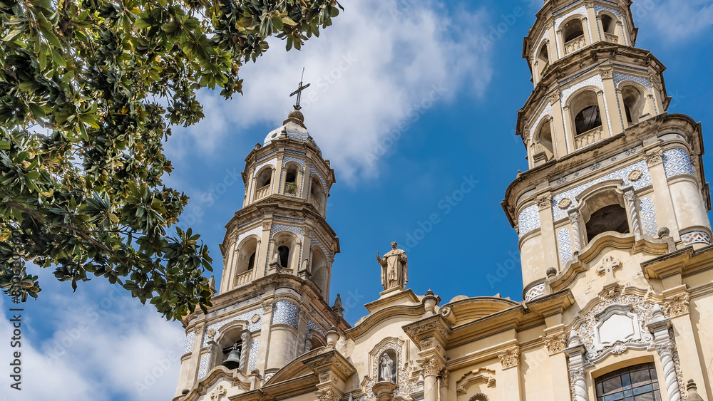 Fototapeta premium An old colonial building in the historic quarter of Buenos Aires. The Church of San Pedro Gonzalez Telmo. Towers with bells, crosses, sculptures, arches, ornaments against the blue sky and clouds.