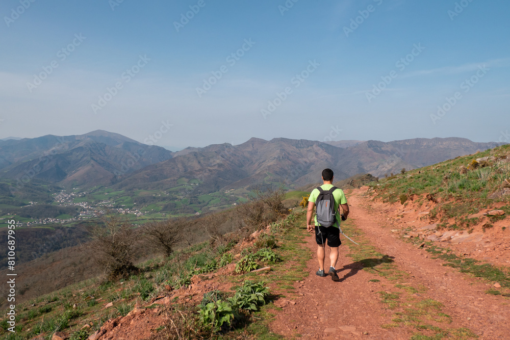 Jovem turista a caminhar numa trilha barrenta no alto da montanha Jara num dia ensolarado