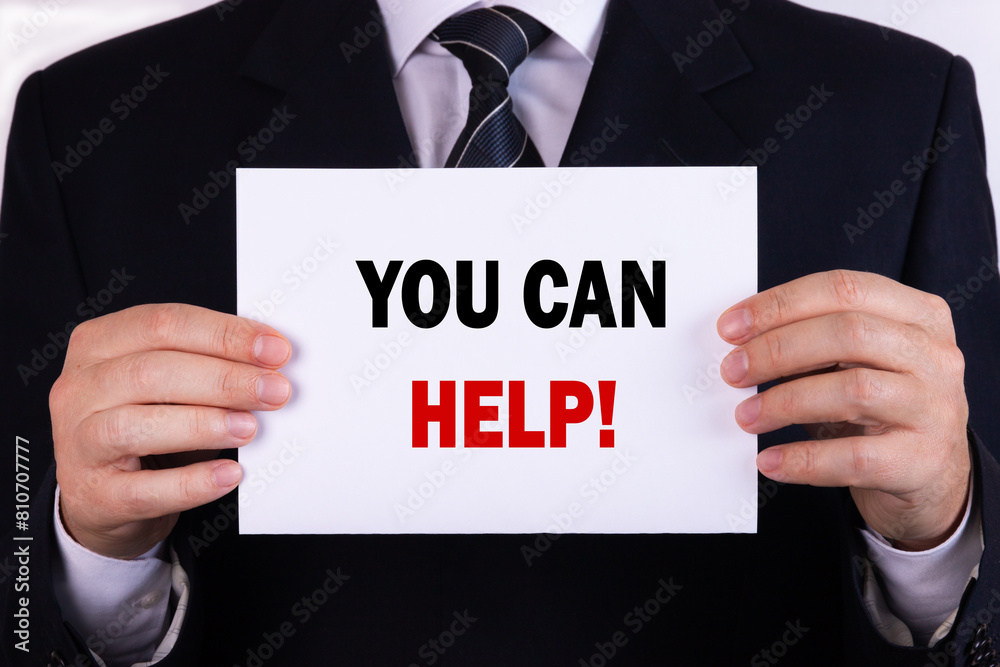 Businessman holding a card with text you can help Businessman holding a card with text you can help