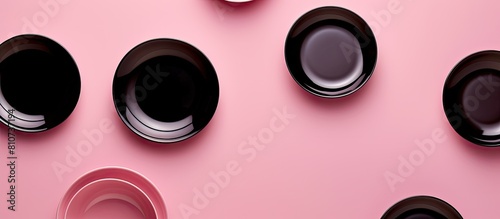 Top view of a pink background showcasing a set of black ceramic plates and gravy boats perfect for copy space images photo