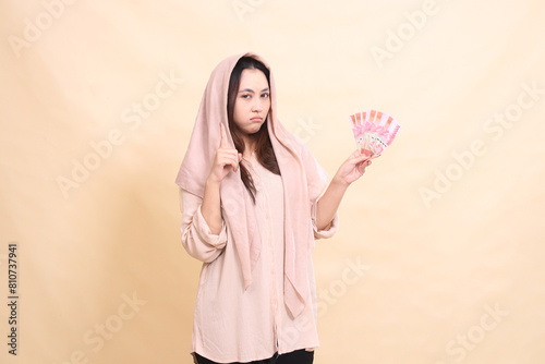 woman indonesia pouting at the camera hands up and carrying rupiah notes. young beautiful for finance  advertising  fashion
