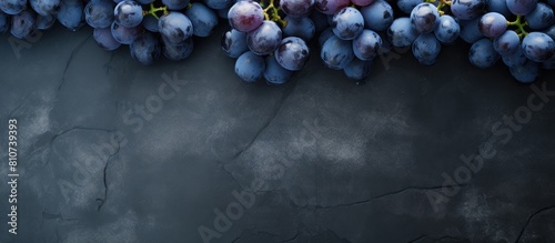 The top view shows a collection of plump ripe blue grapes resting on a dark scratched surface in this copy space image photo