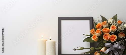 Indoors there is a photo frame adorned with a black ribbon a burning candle placed on a light grey table and a wreath of plastic flowers positioned near the wall This setup provides a suitable backgr