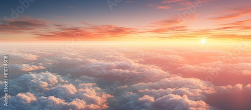 A blurred and noisy copy space image showcases the fiery red sky at great altitude with the sunset reflecting off clusters of dense fluffy white clouds as seen from an airplane window photo