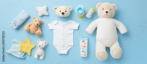 An assortment of baby items including cloth diapers baby powder a nibbler cream a teether a soother and a baby toy arranged on a blue background The image includes copy space and is viewed from the t photo