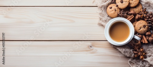 Hello winter A cozy scene unfolds on a light wooden background featuring a cup of tea a scarf delectable cookies and tempting hazelnuts Perfect for a copy space image