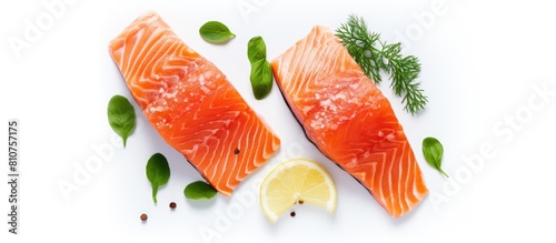 An overhead photo of two salmon slices placed on a white background garnished with lemon garlic pepper and basil provides ample copy space in the frame © HN Works