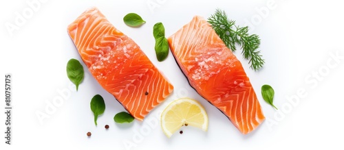 An overhead photo of two salmon slices placed on a white background garnished with lemon garlic pepper and basil provides ample copy space in the frame