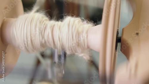 Closeup: Freshly spun wool yarn collects on bobbin of spinning wheel photo