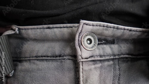 Close-up of a man unbuckling a tactical black belt from his trousers photo