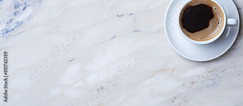 A copy space image of a coffee cup can be seen from a top view position on a marble table background © HN Works