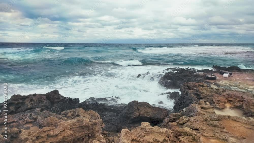 Waves break with force upon coastal rocks, spraying water into the air, under a cloudy sky. Waves break with force upon coastal rocks, spraying water into the air, under a cloudy sky.