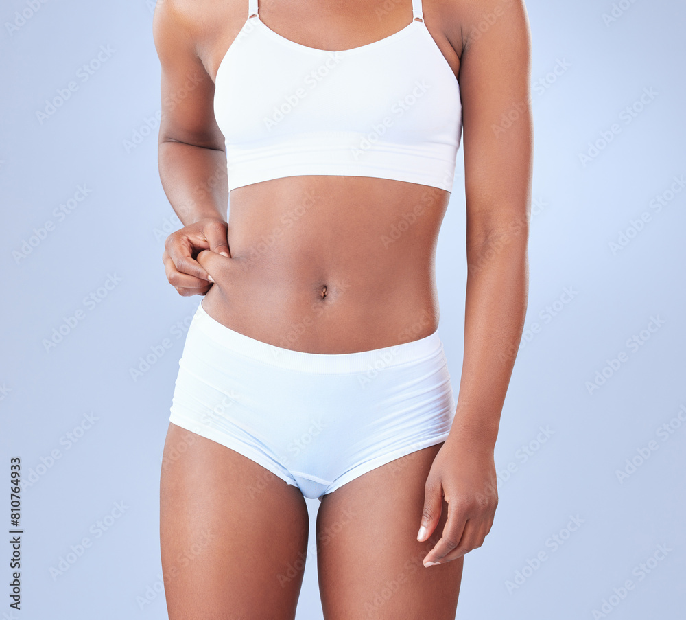 Black woman, hands and belly fat with weight loss in underwear for tummy tuck or lipsuction on a blue studio background. Closeup of African or female person touching stomach or skin for body or diet Black woman, hands and belly fat with weight loss in underwear for tummy tuck or lipsuction on a blue studio background. Closeup of African or female person touching stomach or skin for body or diet