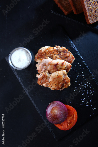 Fresh grilled chicken fillet with spices on a dark background. A dish cooked on fire. Diet food.