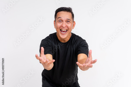 An enthusiastic middle-aged Asian man with outstretched arms, appearing to catch or grope something invisible, isolated on a white background.