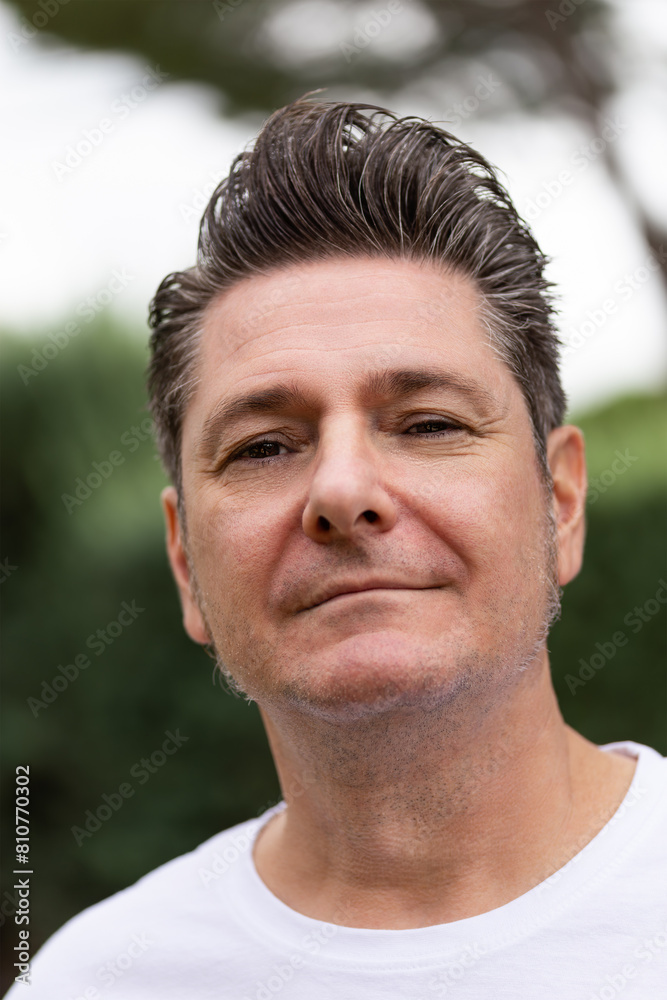 Portrait of an attractive mature man in his 50's with toupee and gray hair, smiling, happy and relaxed looking at camera in an outdoor park on a summer afternoon. Concept of maturity Portrait of an attractive mature man in his 50's with toupee and gray hair, smiling, happy and relaxed looking at camera in an outdoor park on a summer afternoon. Concept of maturity