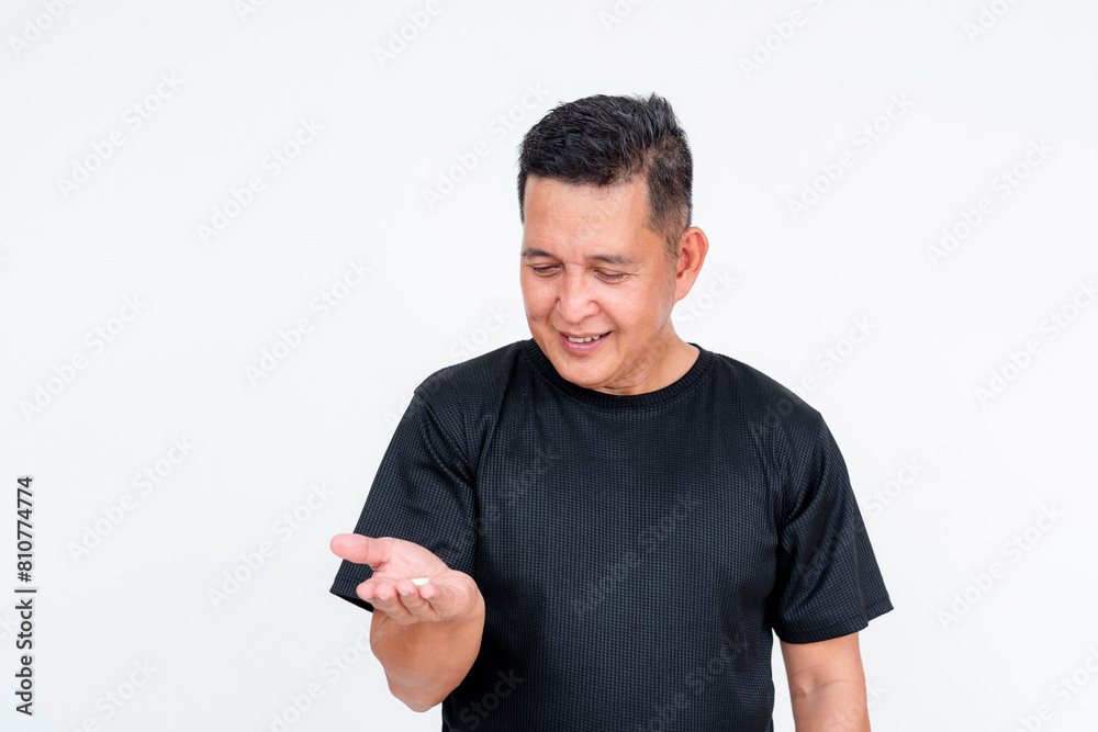 Middle aged Asian man holding antacid pill, isolated on white background Middle aged Asian man holding antacid pill, isolated on white background