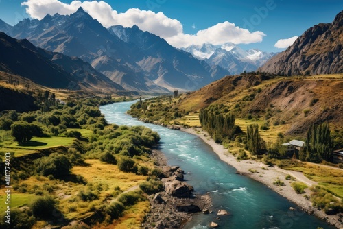 Tajikistan landscape. Majestic River Flowing Through Lush Valley with Snow-Capped Mountains in Background.