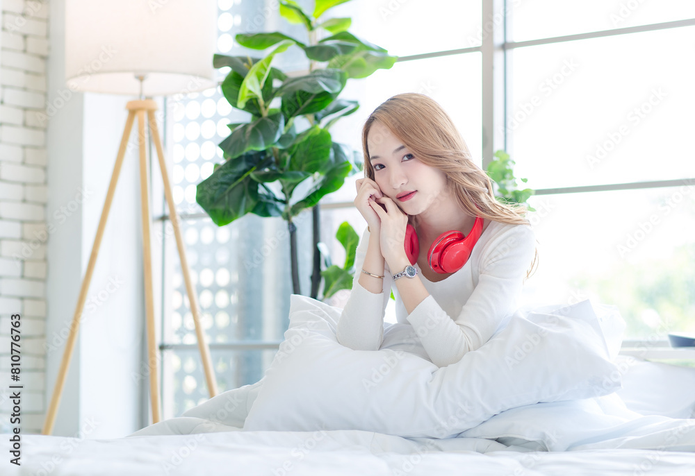 Asian teenage girl beautiful woman in bedroom, feeling happy and smiling relaxed with headphones listening to music having fun after getting up from sleep on bed at home, waking up in the morning. Asian teenage girl beautiful woman in bedroom, feeling happy and smiling relaxed with headphones listening to music having fun after getting up from sleep on bed at home, waking up in the morning.