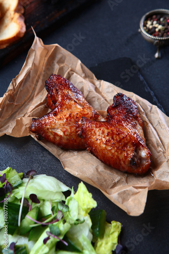 Grilled chicken wings. The grilled wings are laid out on craft paper. An appetizer for beer.