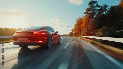 Red sports car in dynamic motion on a forest-lined road during autumn.