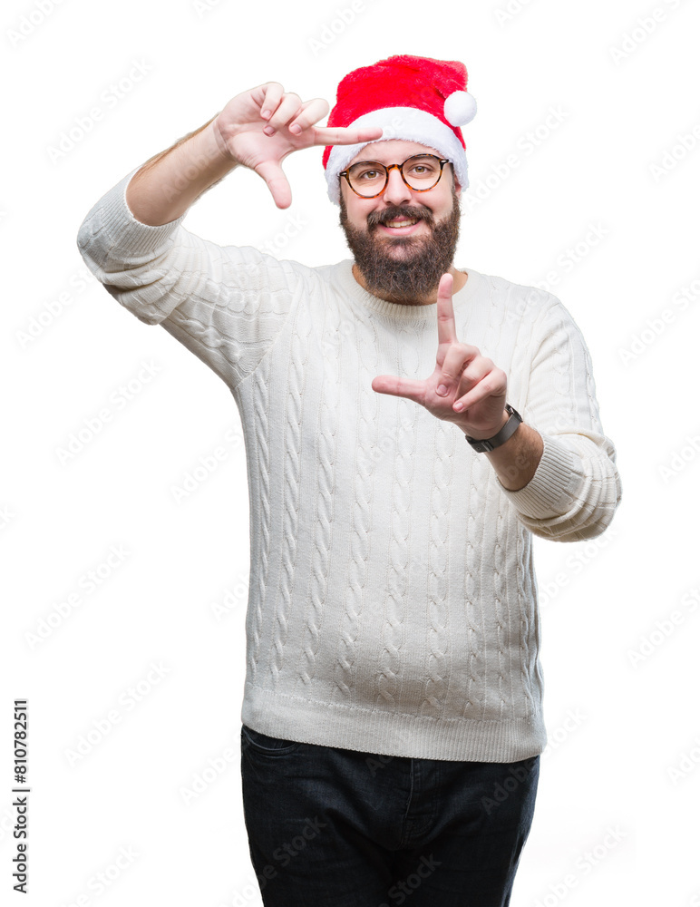 Young caucasian man wearing christmas hat and glasses over isolated background smiling making frame with hands and fingers with happy face. Creativity and photography concept. Young caucasian man wearing christmas hat and glasses over isolated background smiling making frame with hands and fingers with happy face. Creativity and photography concept.