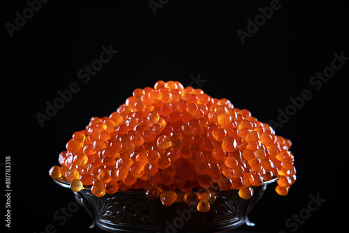 Red caviar in a vase on a black background. Salmon roe. A delicacy. A useful omega. Copy space.
