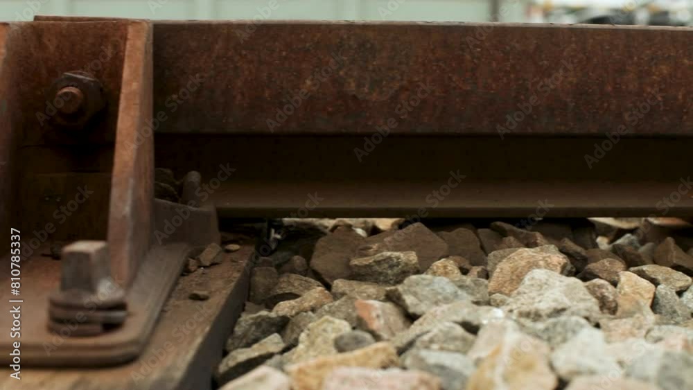 Close-up panning shot of a rusty railroad track with details of bolts and stones Close-up panning shot of a rusty railroad track with details of bolts and stones