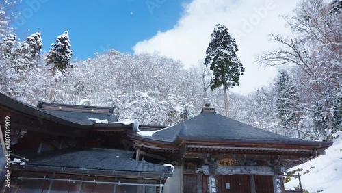 Snow falling over Mountain Temple on Beautiful Winter day in Yamagata Japan photo