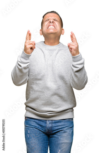 Middle age arab man wearing sport sweatshirt over isolated background smiling crossing fingers with hope and eyes closed. Luck and superstitious concept.