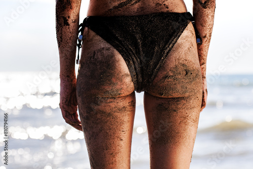 Konstfotografi Sandy beach day: close-up view of woman wearing a black swimsuit