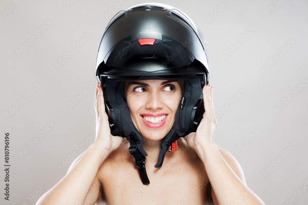 Happy young woman wearing a motorcycle helmet with a playful smile Happy young woman wearing a motorcycle helmet with a playful smile