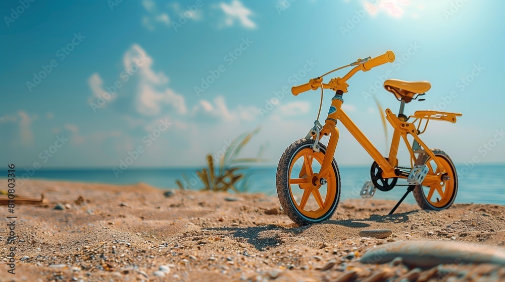 Fototapeta premium Sunshine yellow baby bike with training wheels near a beach, fun summer day,
