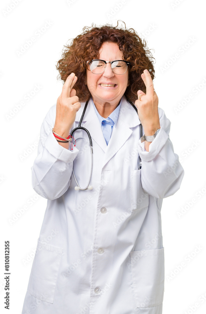 Middle ager senior doctor woman over isolated background smiling crossing fingers with hope and eyes closed. Luck and superstitious concept. Middle ager senior doctor woman over isolated background smiling crossing fingers with hope and eyes closed. Luck and superstitious concept.