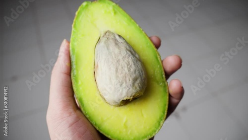 Hands carefully open a ripe avocado, revealing its creamy green flesh