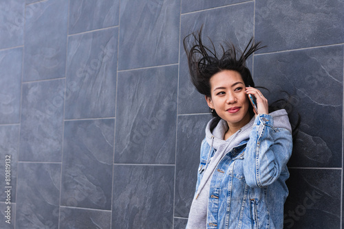 Young beautiful asian woman talking on the phone with a happy face standing and smiling with a confident smile