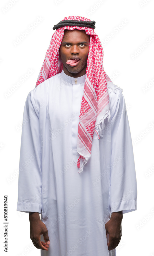 Young arabic african man wearing traditional keffiyeh over isolated background sticking tongue out happy with funny expression. Emotion concept. Young arabic african man wearing traditional keffiyeh over isolated background sticking tongue out happy with funny expression. Emotion concept.