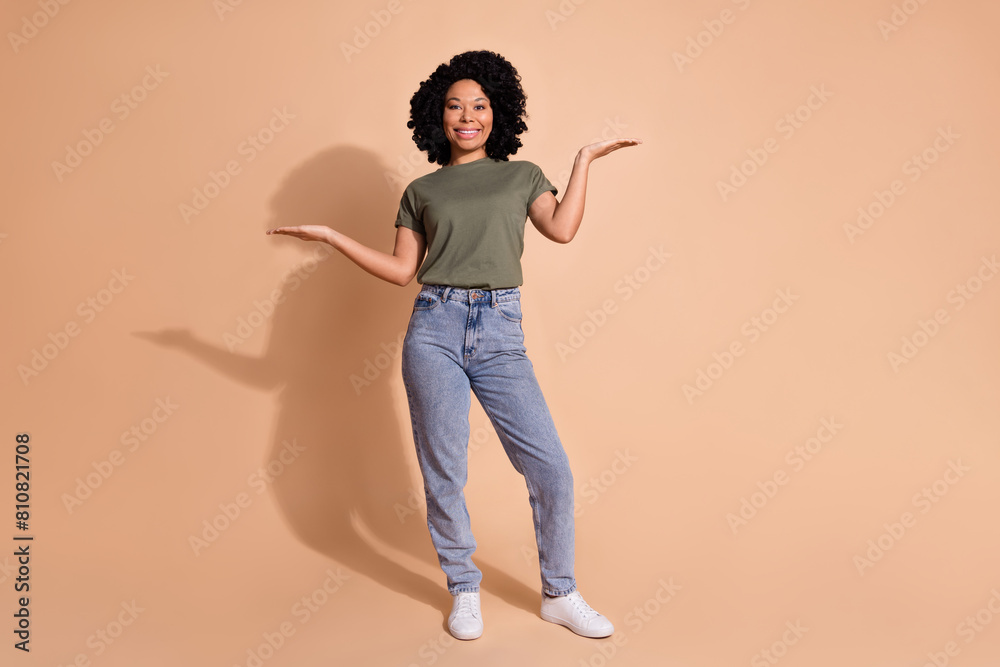 Photo portrait of pretty young woman hands compare empty space dressed trendy khaki outfit isolated on beige color background Photo portrait of pretty young woman hands compare empty space dressed trendy khaki outfit isolated on beige color background