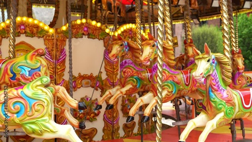 The colorful horses of the carousel move in a circle with speed. Fun place for children in Liverpool