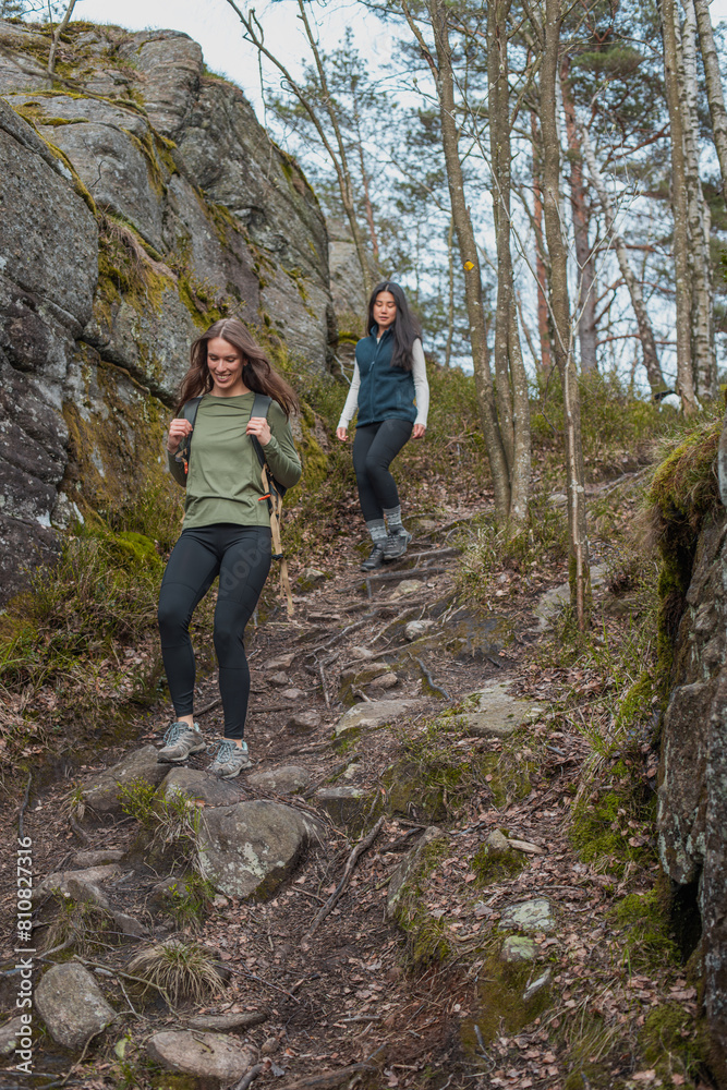 Obraz premium Two young girls going down a hill during a hike in the forest
