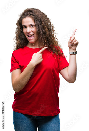 Beautiful brunette curly hair young girl wearing casual look over isolated background smiling and looking at the camera pointing with two hands and fingers to the side.