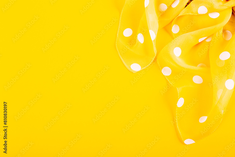 Silk patch of white polka dot fabric on a yellow background. The concept of summer holidays, sewing hobby, handmade workshop, repairing clothes, fabric store card. Bright woman accessory. Copy space Silk patch of white polka dot fabric on a yellow background. The concept of summer holidays, sewing hobby, handmade workshop, repairing clothes, fabric store card. Bright woman accessory. Copy space